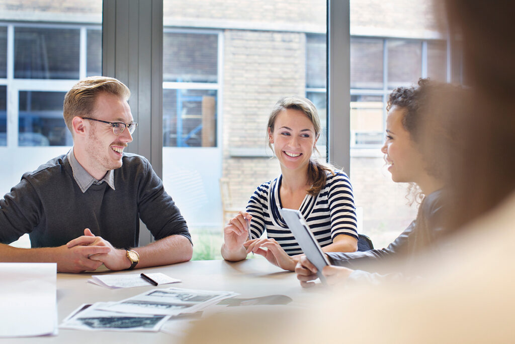 Colleagues sitting at a table smiling during a meeting