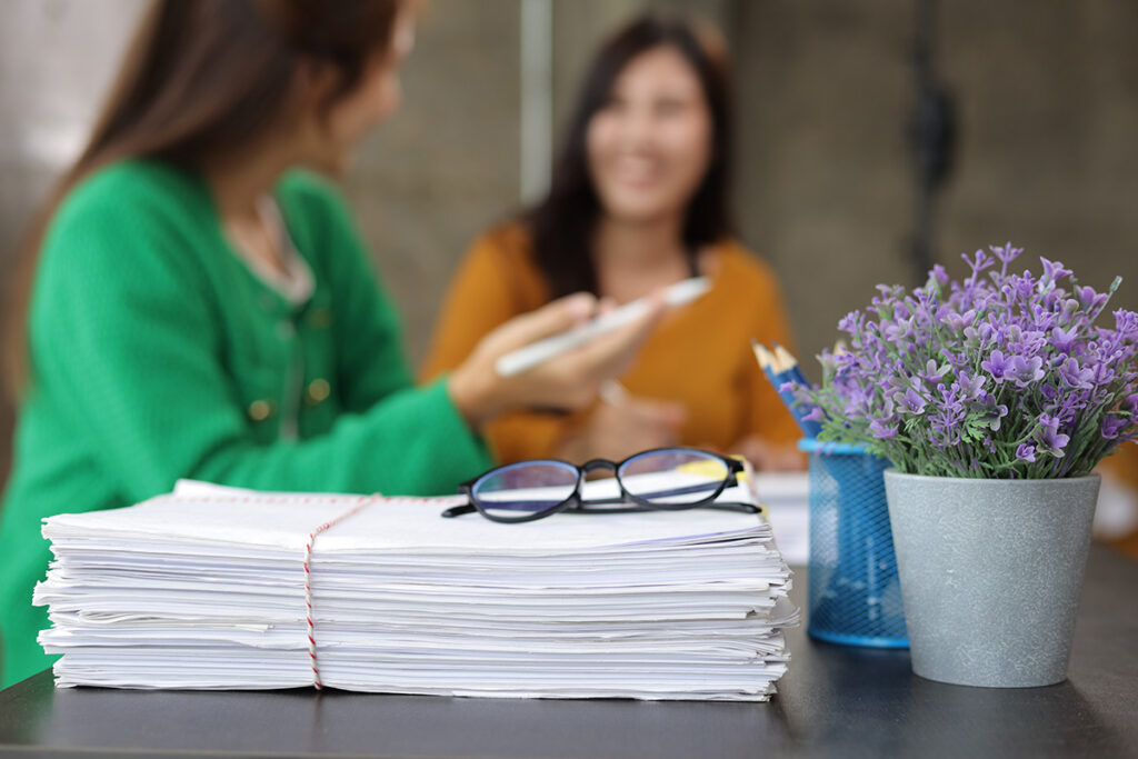 Female colleagues in an office discussing paperwork with the documents in focus and the women blurred in the background